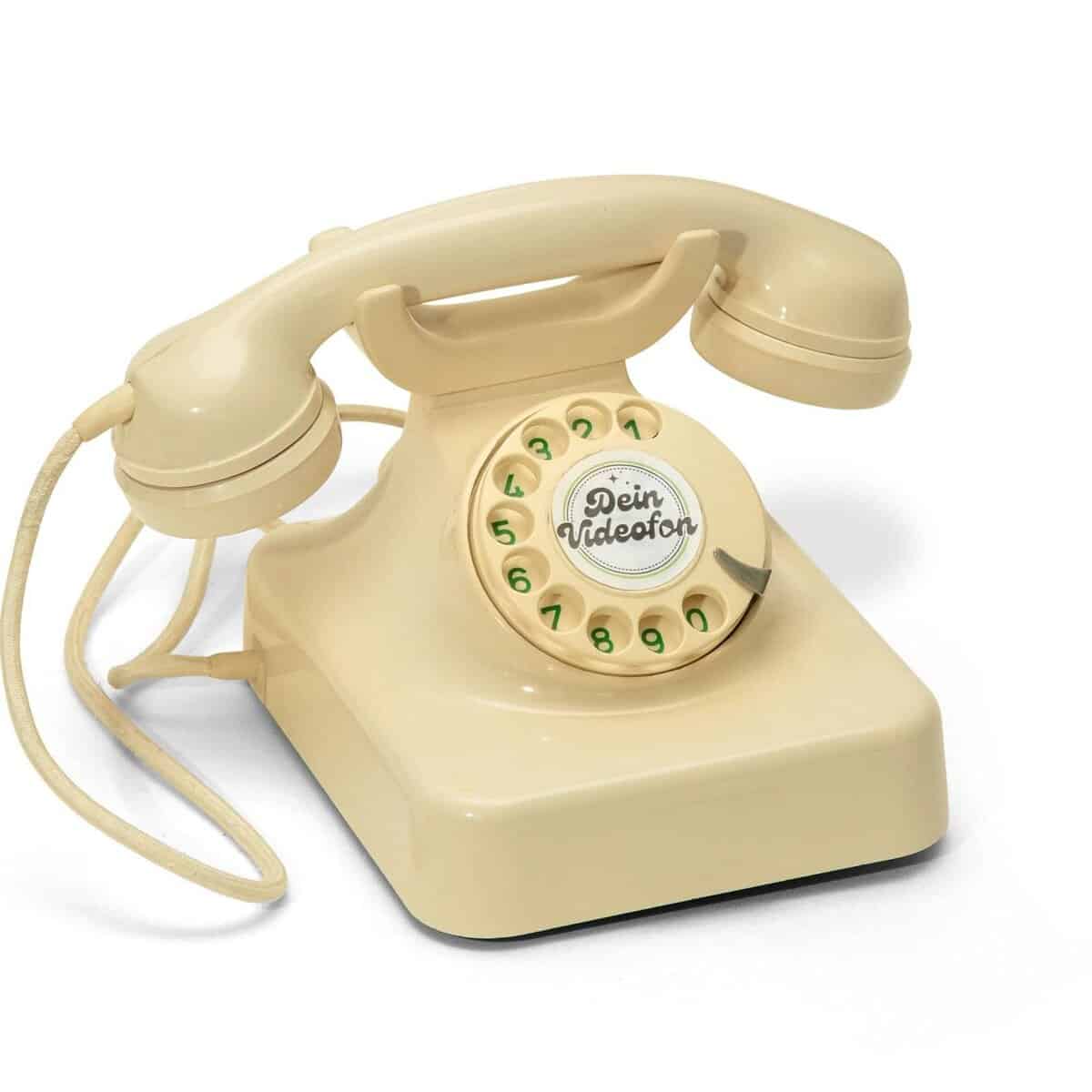 Beigefarbenes Wählscheibentelefon mit einem Spiralkabel und der Aufschrift Dein Videofon in der Mitte der Wählscheibe.